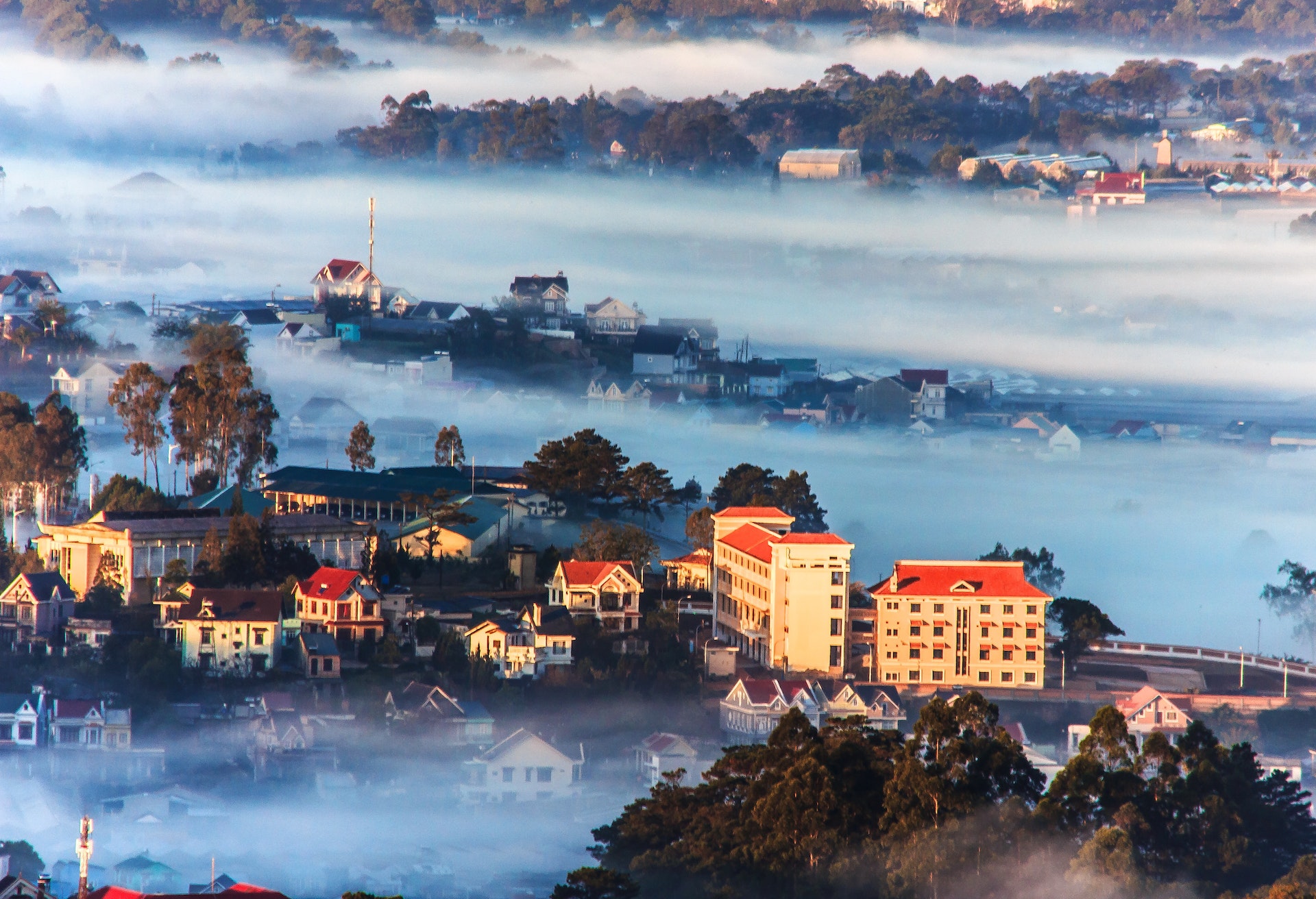 An aerial view overlooking the hill station of Dalat in Vietnam. The town is shroud in mist due to its high altitude, meaning only a few buildings are visible.