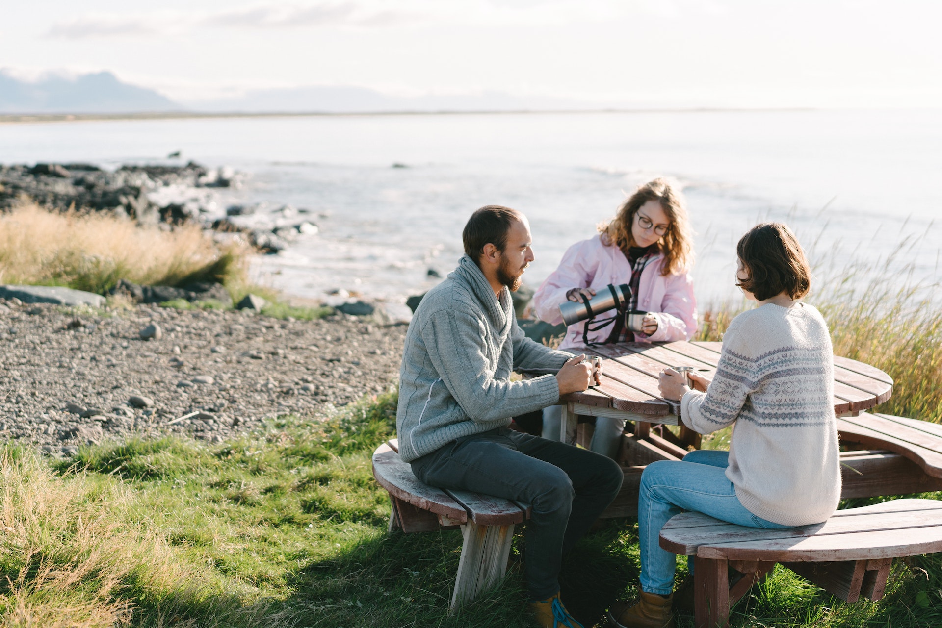 Young Caucasian man and women  sitting  at the table on the beach in Iceland