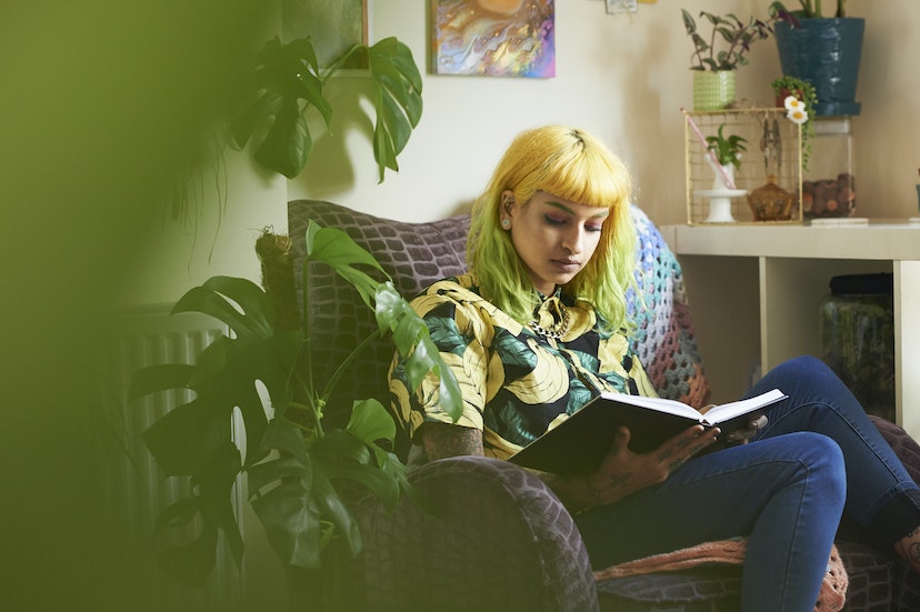 Young hipster woman reading a book in her living room