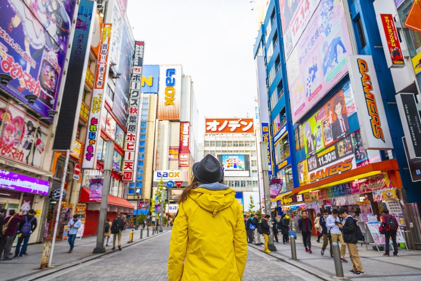 Woman with a yellow jacket walking in the electronic town district of Akihabara. 
