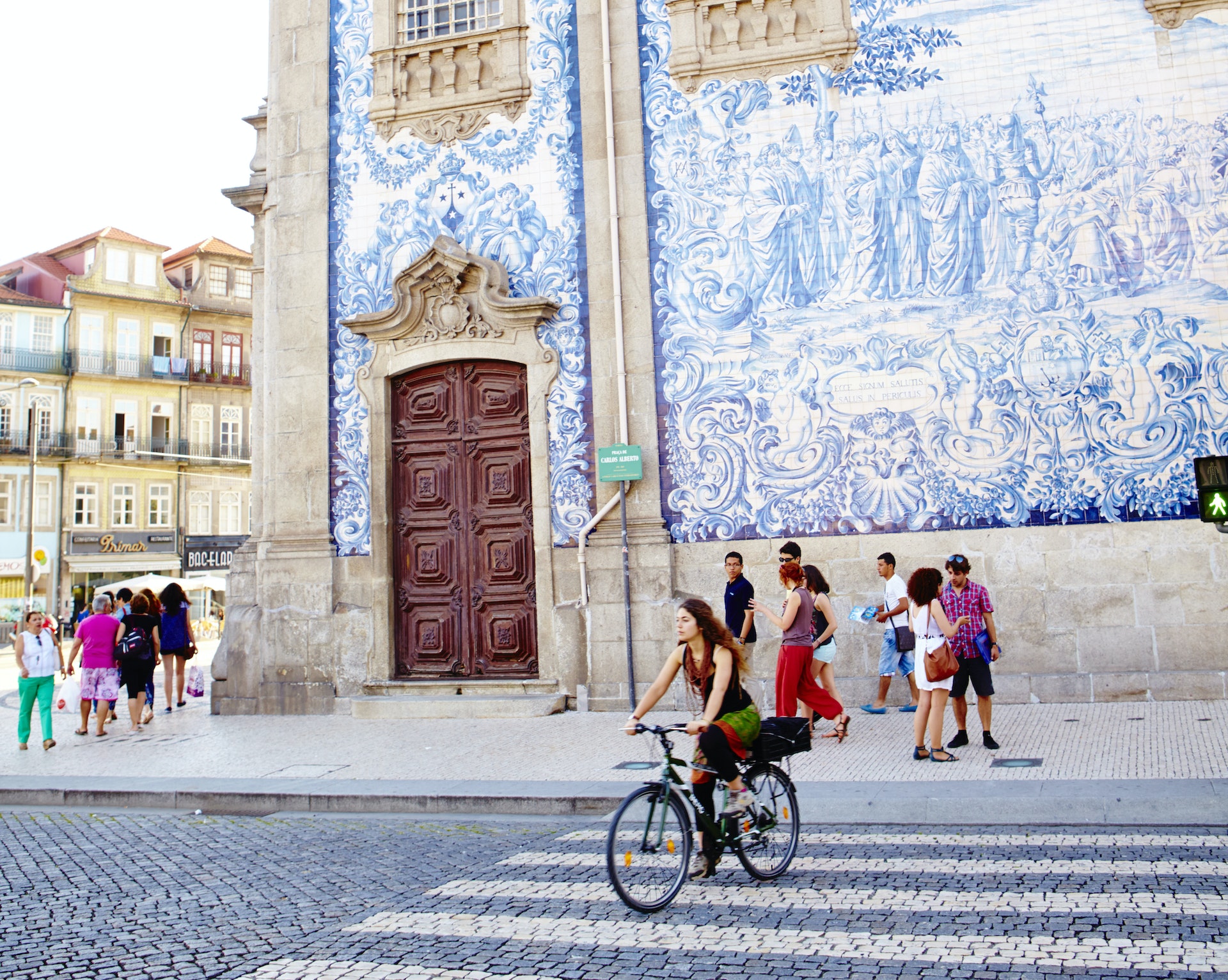 A street scene in Porto with a church wall covered in blue and white tiles in the background