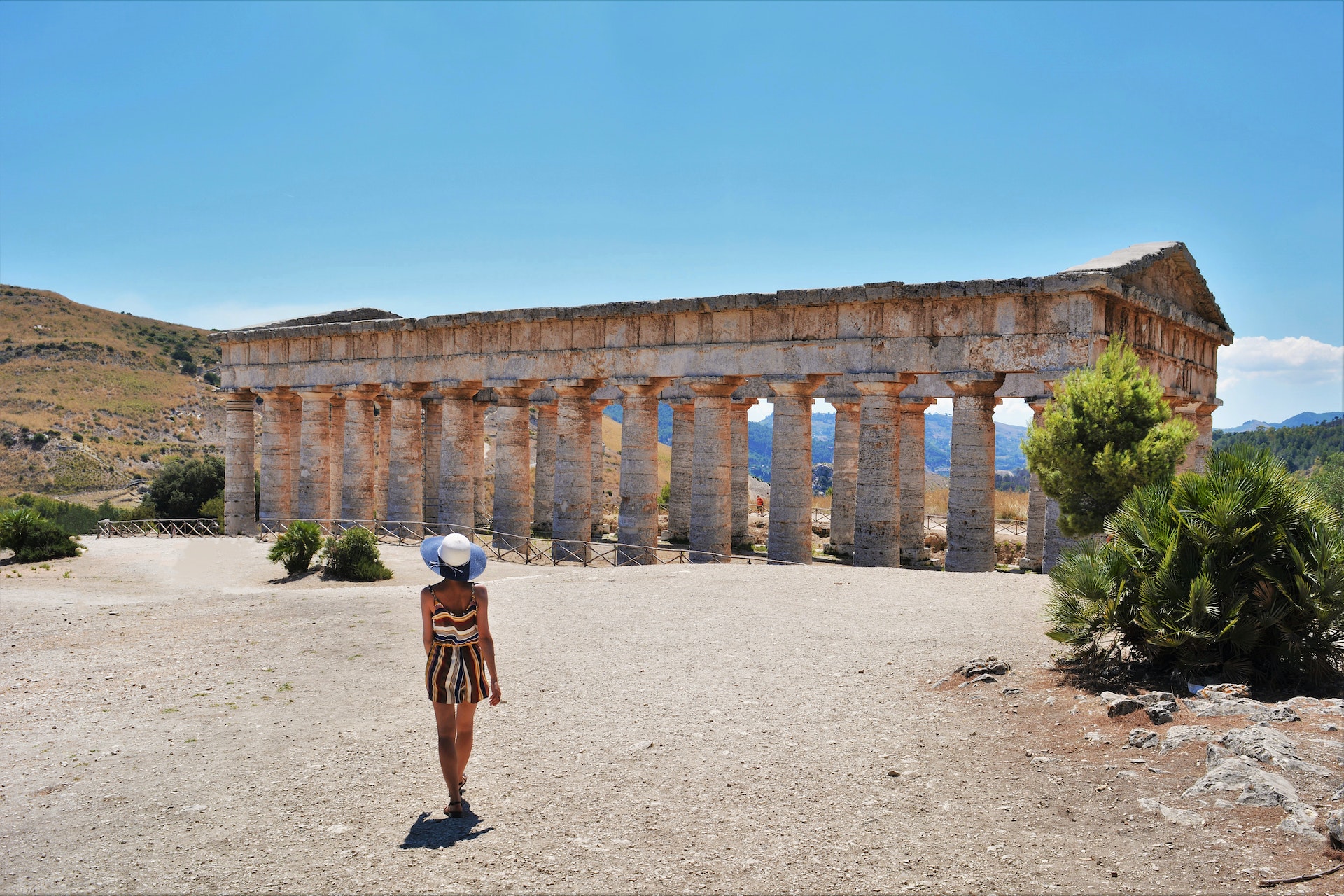 A woman in a jumper and sun hat in front of the Greek temple of Segesta, Sicily, Italy