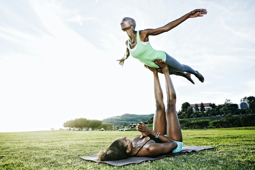 Woman and friend practicing acro yoga in park
